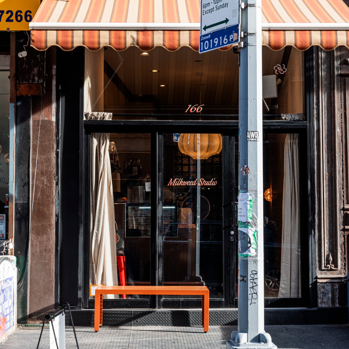 Storefront with striped awning and glass door, street sign visible